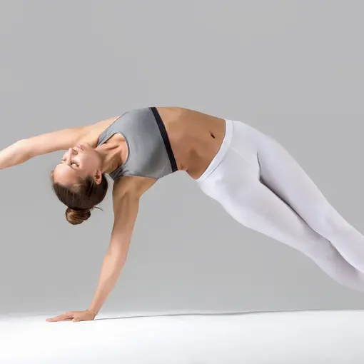 Young woman vasisthasana pose grey studio background
