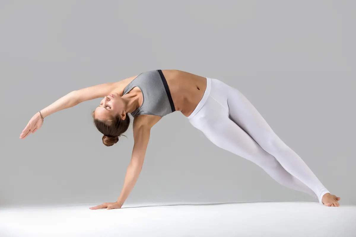 Young woman vasisthasana pose grey studio background